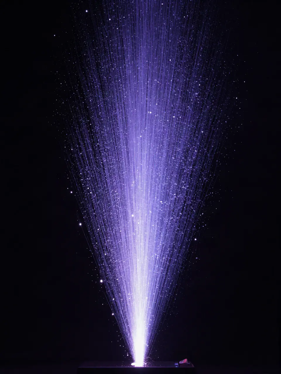 A fountain of fine violet light strands rising from a single point in the dark