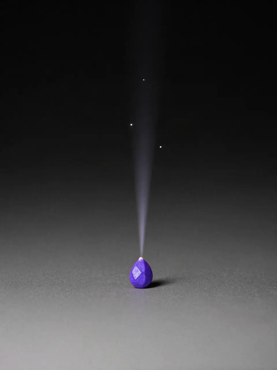 A violet seed on a grey surface with a thin line of light rising from it